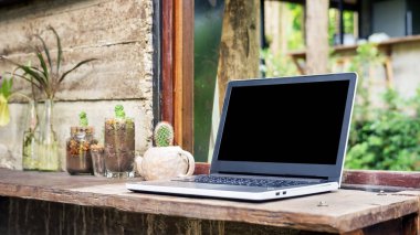 Bir pencerenin yanında dizüstü bilgisayar ve kaktüs.