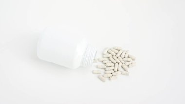 Beyaz arka planda kapsül ilacı ve kase.