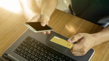 Masada kart, akıllı telefon ve dizüstü bilgisayar kullanan bir adam..