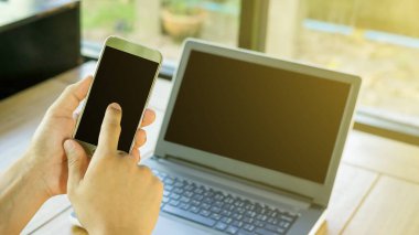 Akıllı telefon ve dizüstü bilgisayar kullanan bir adam, seçici odaklanma.