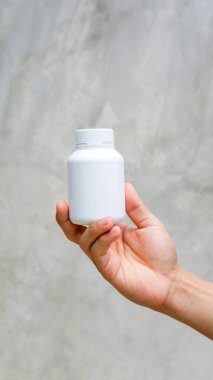 Gri arka planda beyaz bir ilaç kasesi tutan adam..