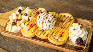 Tahta bir masada ballı tost ve meyveli dondurma..