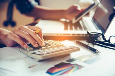 İş adamları hesap makinesi ve iş analizi grafikleri ve belgeler ile akıllı telefon üzerinde çalışıyoruz