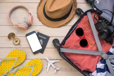 Seyahat pasaportu, cüzdan, gözlük, akıllı telefon cihazları, bavulun ahşap zemininde seyahat etmeye hazır..