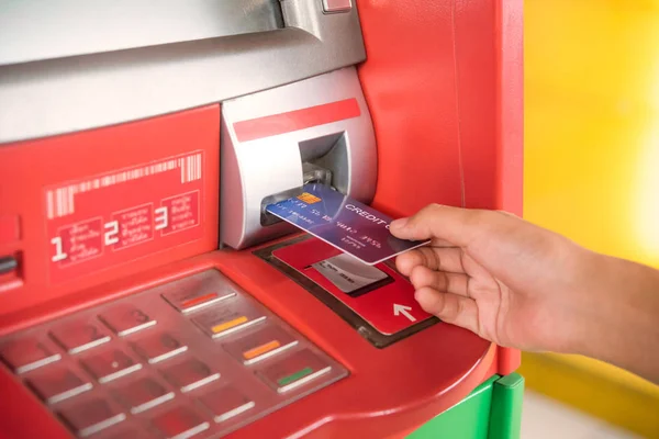 Hand inserting with a credit card into bank machine . Man using an atm machine with  credit card to withdraw money