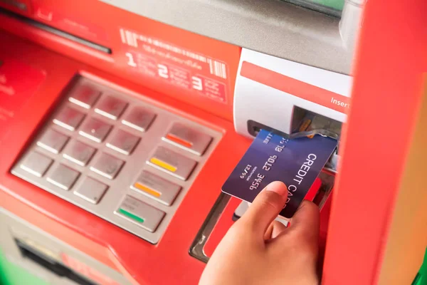 Hand inserting with a credit card into bank machine . Man using an atm machine with  credit card to withdraw money