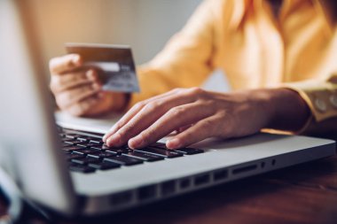 Ellerinde bir kredi kartı tutuyorlar ve online alışveriş yapmak ve finansal işlemler yapmak için mobil cihazlarını kullanan bir ürün hakkında bilgi topluyorlar..