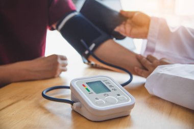 Doktor hastanın tansiyonunu ölçüyor.