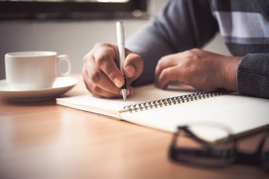 Bir kalem ve Not almak içinde a defter tutan bir adamın elini.