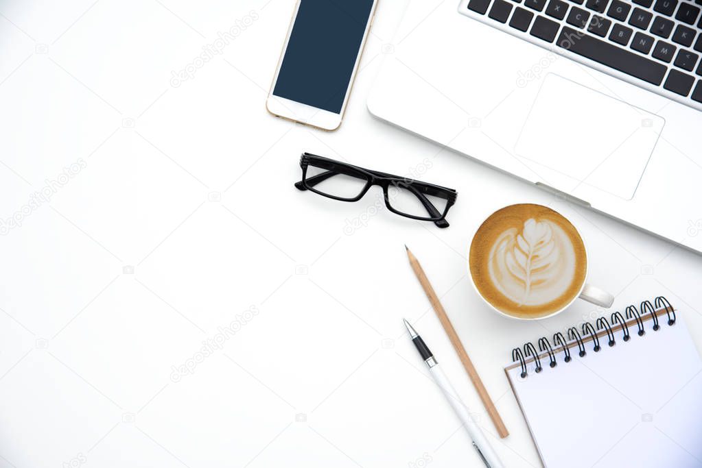 Top view with working desk with laptop,cellphone,notebook pencil coffee cup and eyeglasses in the office. 