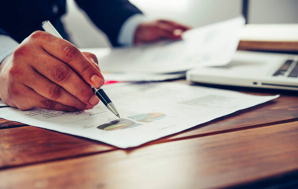 Business people are working on accounts in business analysis with graphs and documentation.