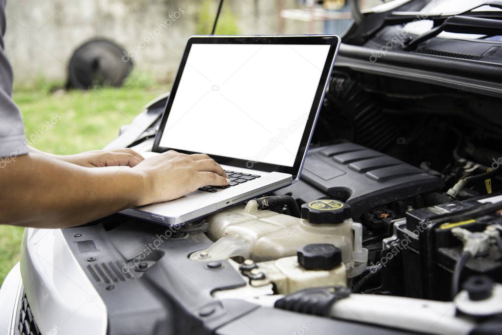 Professional mechanic checking car engine search for data with laptop and connect data system on car