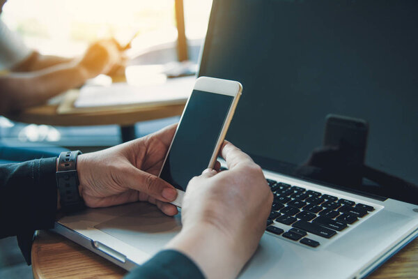 Бизнесмены используют смартфоны и ноутбуки для подключения и поиска информации в офисе
