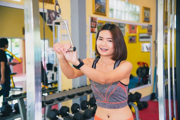 Women exercise in a professional gym with a selection of exercise equipment.