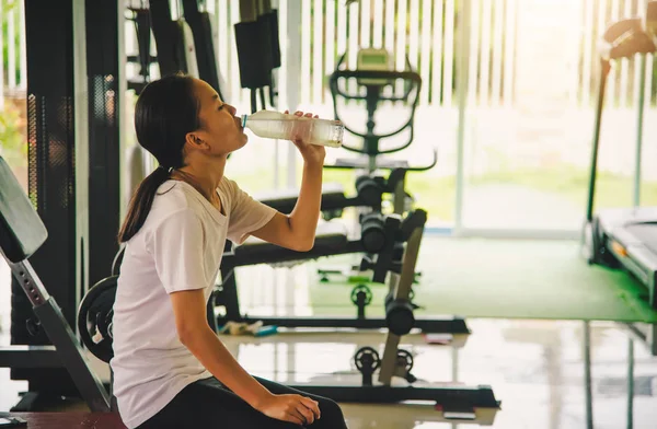 Girl drinking water after sweat from exercise at gym