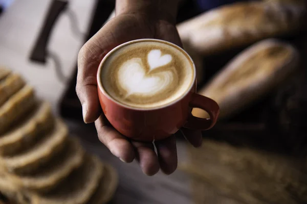 Barista\'s hands are delivering coffee to customers.