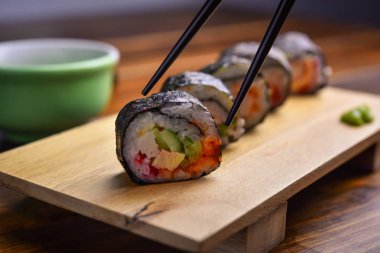Suşi ahşap tabakta yuvarlanıyor.