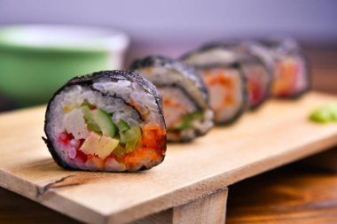 Suşi ahşap tabakta yuvarlanıyor.