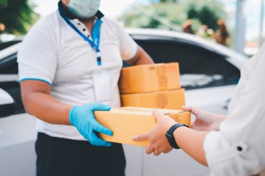 Erkek teslimat işçileri, covid19 sırasında güvenli kullanıcılara hizmet sunarak mal veya paket dağıtmak için temizlik yüzü takar ve eldiven giyerler..