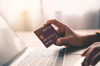Kredi kartını tutan elleri kapat, dizüstü bilgisayarın klavyesine yaz, online alışveriş yap. 