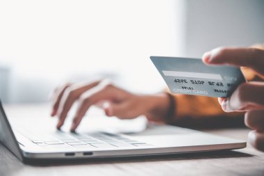 Kadının eli kredi kartı tutuyor ve dizüstü bilgisayarla çalışıyor. Çevrimiçi alışveriş için çevrimiçi ödeme