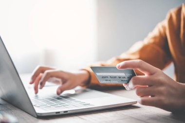 Kadının eli kredi kartı tutuyor ve dizüstü bilgisayarla çalışıyor. Çevrimiçi alışveriş için çevrimiçi ödeme