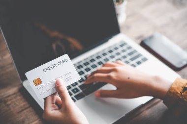 Kadının eli kredi kartı tutuyor ve dizüstü bilgisayarla çalışıyor. Çevrimiçi alışveriş için çevrimiçi ödeme