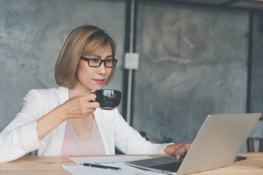 İş kadını kahve içiyor ve laptopta arama yapıyor.