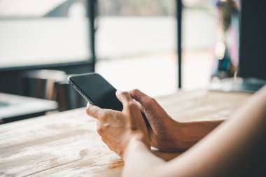 Asyalı iş kadını eli beyaz boş ekranlı akıllı telefonu kullanıyor ve ona dokunuyor..