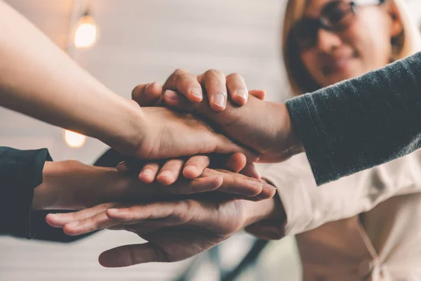 Hands of business people come together in a stack of hands to symbolize collaboration, teamwork to achieve goals and success.