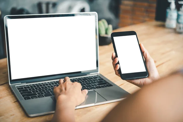 Dizüstü bilgisayarda çalışan bir kadının el görüntüsü ve masaüstünde boş beyaz masaüstü fotokopi ekranı olan akıllı bir telefon.