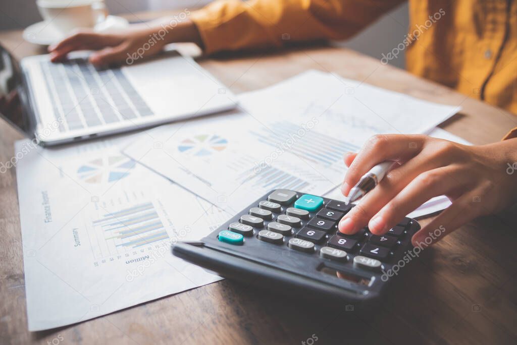  business person sitting at a desk at an office By using the calculator to work. Business Concept Analysis and Planning