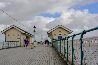 Penarth, Cardiff / Wales UK - 5 Temmuz 2020: Penarth Viktorya İskelesi 'nde haftalarca kilitli kaldıktan sonra nihayet açıldı. Aileler, arkadaşlar fırtınalı gökyüzünün altında fırtınalı rüzgarda sahil boyunca yürür.
