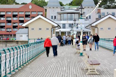 Penarth, Cardiff / Wales UK - 5 Temmuz 2020: Penarth Viktorya İskelesi 'nde haftalarca kilitli kaldıktan sonra nihayet açıldı. Aileler, arkadaşlar fırtınalı gökyüzünün altında fırtınalı rüzgarda sahil boyunca yürür.