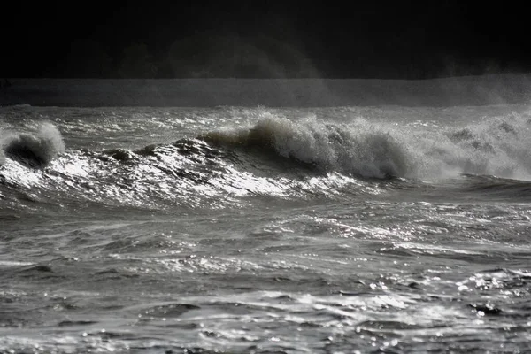 強風と満潮の荒波が岩の多い海岸に大波を作り出します 夕日が水面を照らし スプレーが水面に霧を作り出します — ストック写真