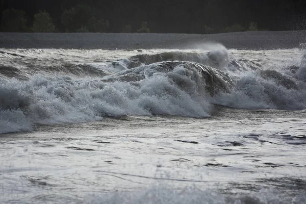 強風と満潮の荒波が岩の多い海岸に大波を作り出します 夕日が水面を照らし スプレーが水面に霧を作り出します — ストック写真