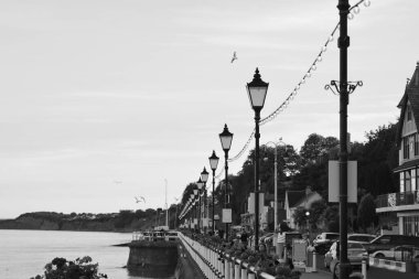 Güneş battı ve insanlar Penarth gezinti güvertesi ve iskele boyunca akşam yürüyüşünün tadını çıkarıyor. Viktorya dönemi pavyonu bu sahil kasabasında çok iyi bilinen bir simgedir ve insanlar tahta kaldırım boyunca yürümeyi severler.