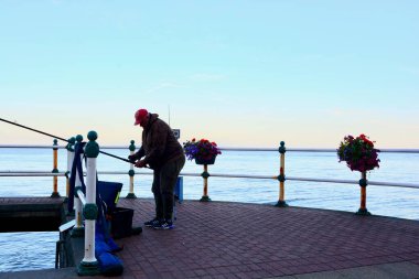 Güneş battı ve insanlar Penarth gezinti güvertesi ve iskele boyunca akşam yürüyüşünün tadını çıkarıyor. Viktorya dönemi pavyonu bu sahil kasabasında çok iyi bilinen bir simgedir ve insanlar tahta kaldırım boyunca yürümeyi severler.