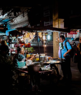 BANGKOK, THAILAND - Aralık 2019: İnsanlar gece sokak gıda pazarından yiyecek satın alıyorlar.
