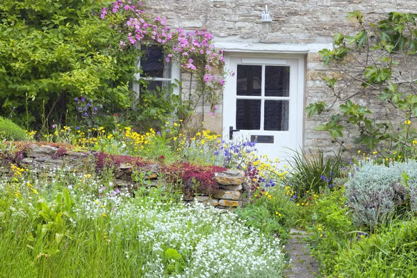 白色木门在一个迷人的英国乡村小屋与前面的花园盛开的花朵 粉红色的玫瑰 无花果树爬上石墙 — 图库照片