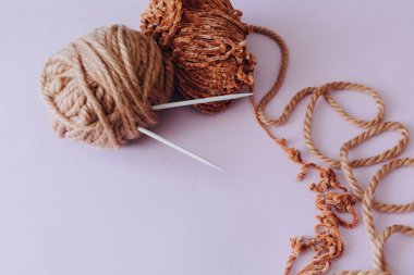 Üst Manzara. Örgü örmek ve örgü örmek için iplik. İpliğe saplanmış örgü iğneleri. Farklı tip tığ işi kancaları. Ahşap bir arka planda. Hobi konsepti.