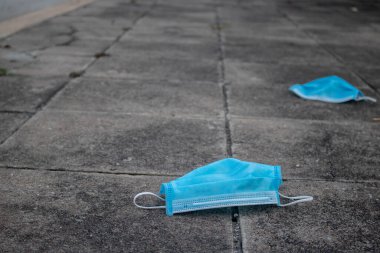 Mavi tek kullanımlık tıbbi maske beton yol yüzeyinde. Virüs Covid-19 'u önlemek için. Kavramsal virüsler tüm dünyaya yayıldı. seçici fofus. Boşluğu kopyala.