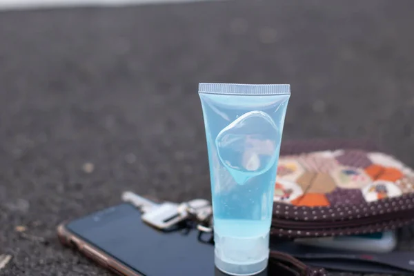 一种蓝色的酒精凝胶瓶 放在灰色的背景上 装有日常设备 如手机 家用钱包和碎屑 洗手用的酒精凝胶 Covid 19防毒 防毒复制空间 — 图库照片