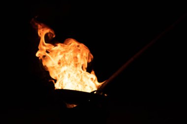 Arkaplan için bulanık ve bulanık görüntü. Kavrulmuş kaju tavasındaki ateşten çıkan kırmızı turuncu alev.