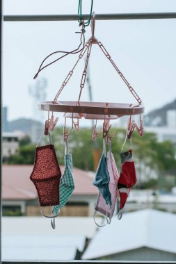 Odanın penceresinin üzerinde kumaştan yapılmış el yapımı maskeler asılı. Yıkanabilir ve yeniden kullanılabilir. Koroner virüs salgını nedeniyle cerrahi maske kıtlığında kullanılabilir. Covid-19. Boşluğu kopyala