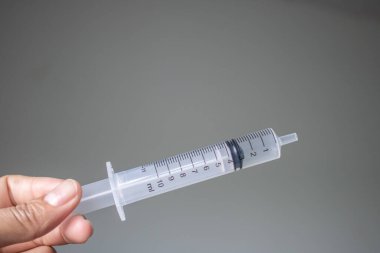 Beyaz arka planda şırıngayı tutan el.