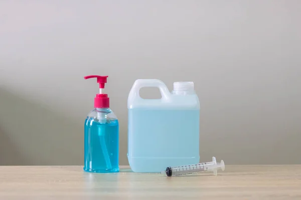 Blue alcohol gel bottles and gallons, syringe. Put on the table and white walls, alcohol, hand wash. Anti-virus and anti-virus Covid-19 Copy space.