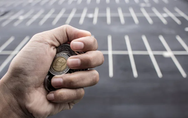 Clutch a coin to save money. The economy was bad during the epidemic. holding the coins and the background is a gray road. in saving money concept. copy space