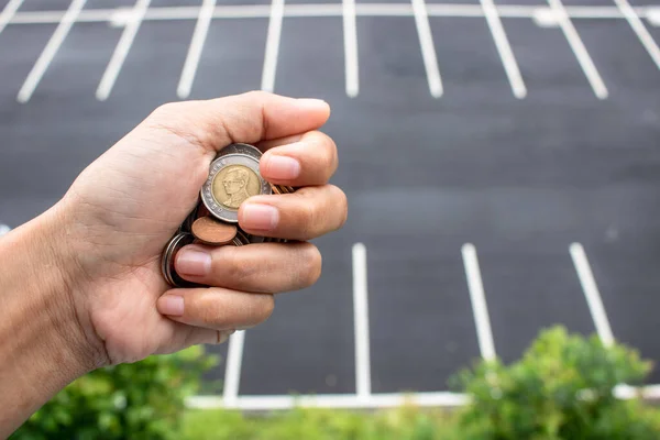 Clutch a coin to save money. The economy was bad during the epidemic. holding the coins and the background is a gray road. in saving money concept. copy space