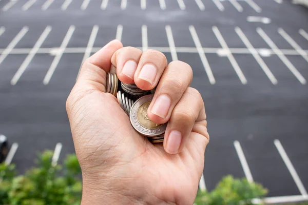 Clutch a coin to save money. The economy was bad during the epidemic. holding the coins and the background is a gray road. in saving money concept. copy space